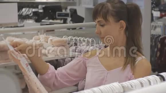 宝贝服装店里漂亮的女人白种人女性选择婴儿服装的特写视频的预览图