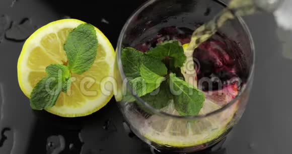 把水倒在一个杯子里里面放着薄荷石灰柠檬醋栗冰块视频的预览图