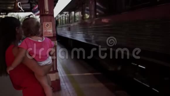 母亲和孩子站在泰国华欣的火车站向出发的火车挥手旅费视频的预览图