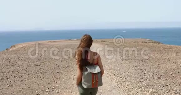 年轻的女性背包客享受海风看着她面前的福尔特文图拉岛徒步旅行者女孩走路视频的预览图
