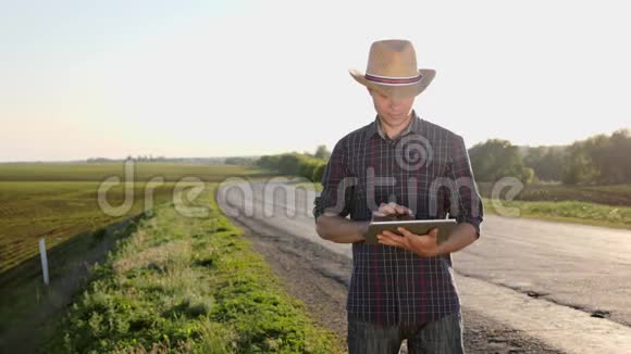 戴着帽子的农夫站在路上用数码平板电脑视频的预览图