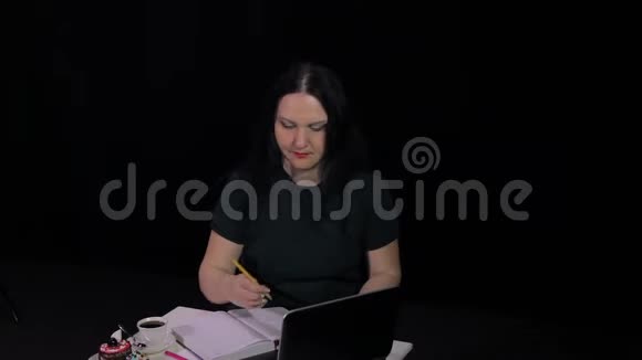 一个在咖啡馆的桌子旁沉思的女人在电脑旁工作喝咖啡视频的预览图