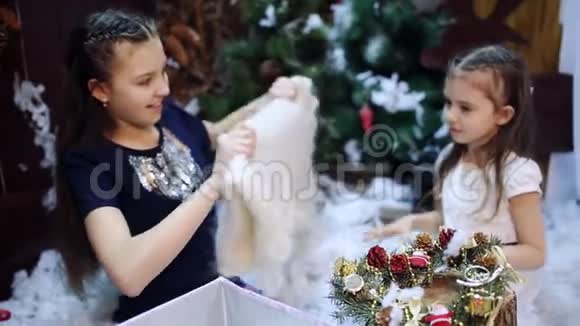 两个小女孩在一棵圣诞树上为礼物孙女们把一条白色披肩作为礼物视频的预览图