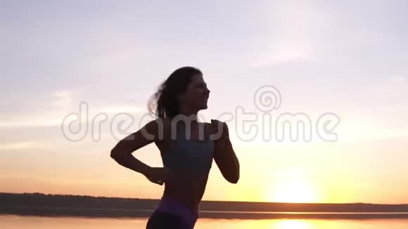 关闭一个健康的女孩在水中奔跑的镜头日出这位年轻妇女接受培训开心微笑视频的预览图