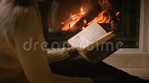 在燃烧的壁炉灯光下美丽的欧伊女人在夜间看书的慢动作视频视频的预览图