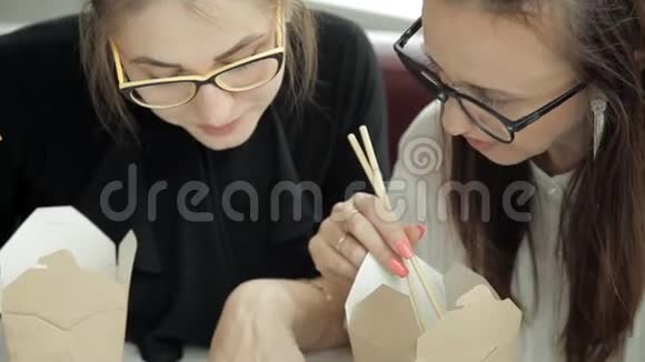 两个年轻的商业女孩坐在咖啡馆里吃着米饭讨论着商业发展工作吃东西视频的预览图