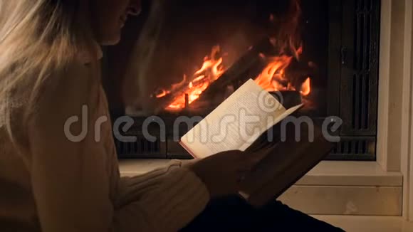 慢动作视频年轻女子阅读书籍和翻页从燃烧的火焰杯视频的预览图