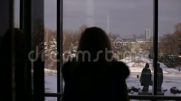 冬天一个女孩靠近一扇大窗户的剪影视频的预览图