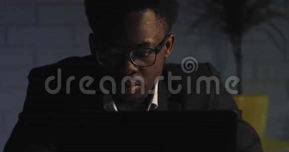 厌倦了在电脑上工作年轻的黑人男子举起眼镜擦眼睛工作狂努力工作视频的预览图