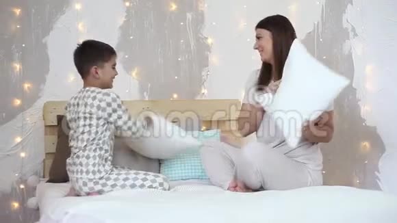一个女孩和一个小男孩坐在床上玩着打对方的游戏高清高清视频的预览图