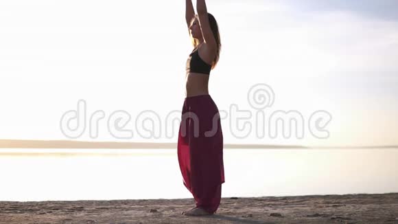 穿着瑜伽服的女人在海滩和水前做瑜伽各种姿势瑜伽姿势眼镜蛇冥想阿萨纳视频的预览图