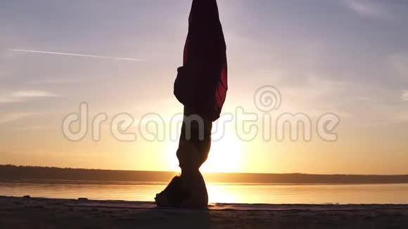 特写镜头一个美丽的女孩站在她的头上瑜伽体式太阳照耀背景上有水视频的预览图