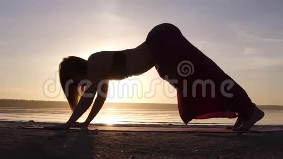 一个女人在海滩上做乌尔达瓦穆卡什万萨纳的剪影镜头后弯太阳照耀着背景视频的预览图