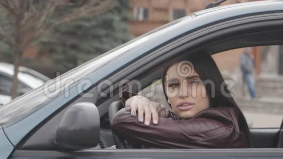 悲伤的年轻女子坐在城市的一辆车里在车里等着的女孩视频的预览图