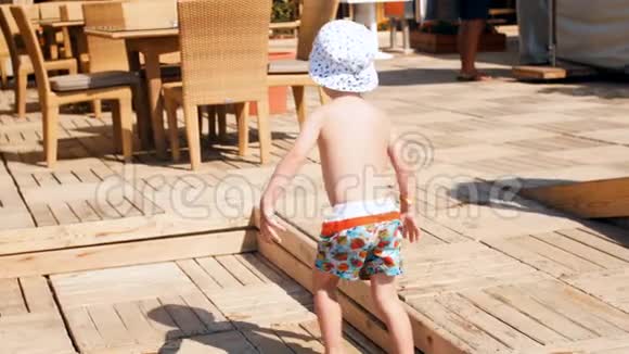 4k镜头快乐微笑的幼儿男孩走在木制码头与咖啡馆在海边视频的预览图
