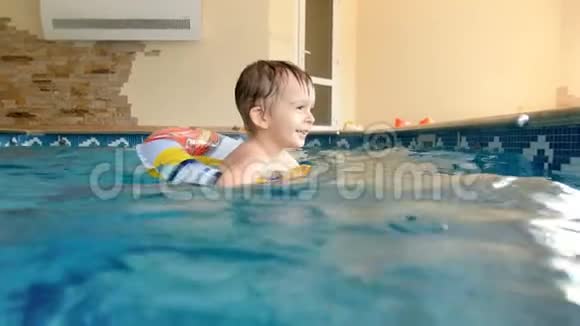 4k小男孩带充气戒指在户外游泳池游泳的视频视频的预览图