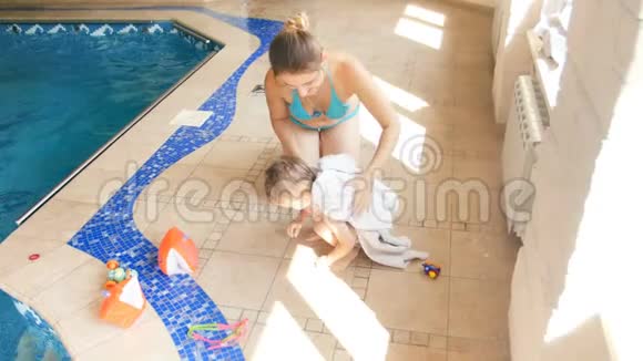 4k视频年轻母亲在游泳池玩耍后用毛巾擦拭湿孩子视频的预览图