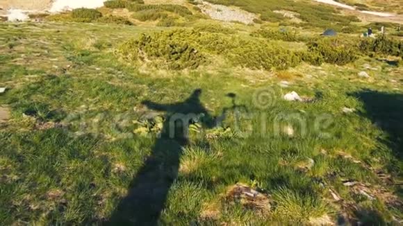 一个高高在上的人在绿色草坪上缓慢地举起一个万向节的影子视频的预览图