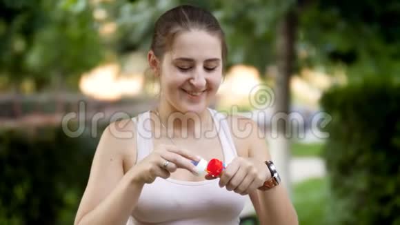 4K镜头美丽的微笑的年轻女子在公园日落时制作肥皂泡视频的预览图