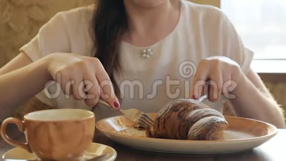 年轻女子在咖啡馆里吃牛角面包唱咖啡视频的预览图