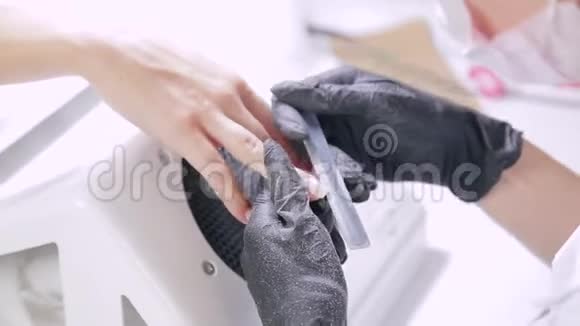 戴手套的美甲师在涂胶前用指甲锉钉客户视频的预览图