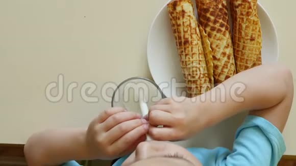 一个快乐的孩子坐在桌边喝牛奶吃晶圆管从上面看视频的预览图