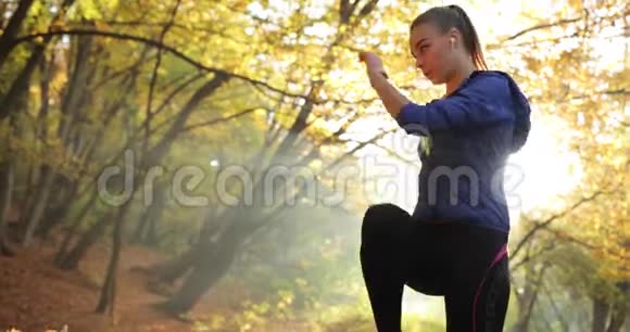秋天公园里的女跑步者穿着慢跑服的疲惫的年轻女子站在秋天公园的朝阳下视频的预览图