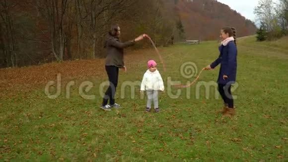 年轻的母亲在秋林里和孩子们玩耍小美女跳绳一家人很幸福视频的预览图