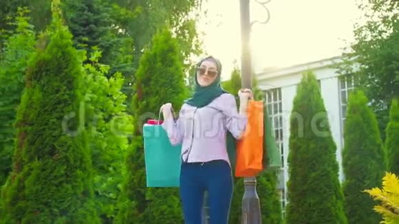 年轻的穆斯林妇女戴着头巾购物后手里拿着包转圈视频的预览图
