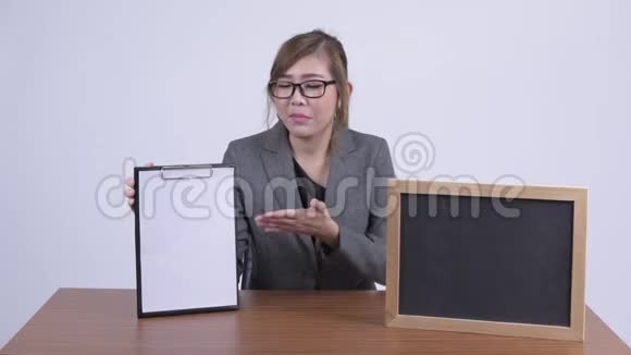 年轻快乐的亚洲女商人展示剪贴板和黑板视频的预览图