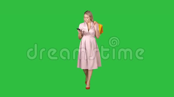 购物妇女带着袋子在智能手机上发短信而走在绿色屏幕上Chroma键视频的预览图