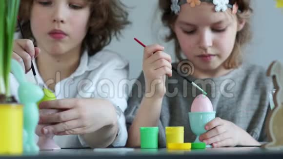有趣的学童用流苏装饰复活节彩蛋女孩拿着一个粉红色的鸡蛋幸福家庭复活节视频的预览图