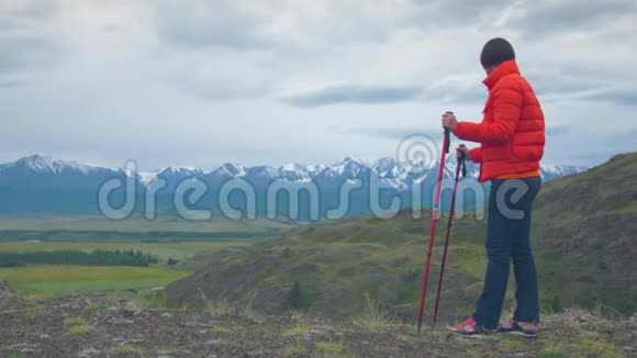 山里的旅行者站在岩石上靠在瑞典的棍子上视频的预览图