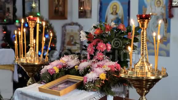 一个乡村东正教教堂的教堂板块燃烧的蜡烛许多花和图标视频的预览图