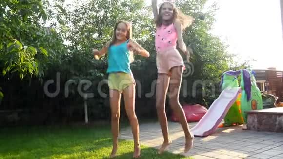 两个十几岁的女孩在炎热的夏日在后院享受雨的4K镜头视频的预览图