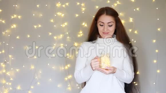 新年圣诞节美丽的女人穿着温暖的白色毛衣手里拿着一盏灯闭上眼睛梦见了视频的预览图