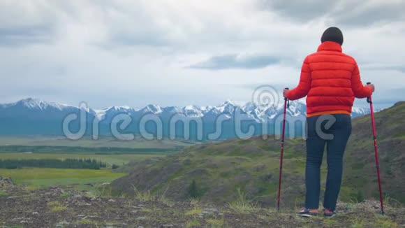 一位登山旅行者站在岩石上靠在瑞典的棍子上视频的预览图