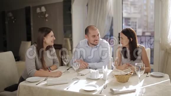 一个男人和两个女人在餐厅的一张桌子上等待你的点菜视频的预览图