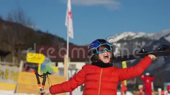 快乐男孩戴着头盔滑雪护目镜棍棒和滑雪板在滑雪场的手中开心孩子在胡闹视频的预览图