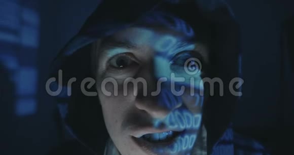 关闭疯狂黑客程序员在引擎盖与二进制代码反射在他的脸在黑暗的房间晚上肖像视频的预览图