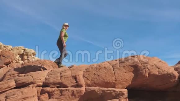 一个活跃的女人爬上红岩升起背景天空视频的预览图