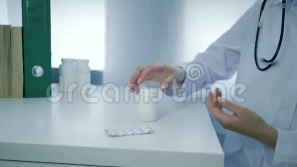 医生双臂打开一罐营养补充剂将黄色的圆形药丸倒入白色桌子上的手掌中视频的预览图