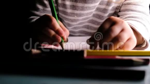 小女孩在一张纸上画绿色铅笔特写视频的预览图
