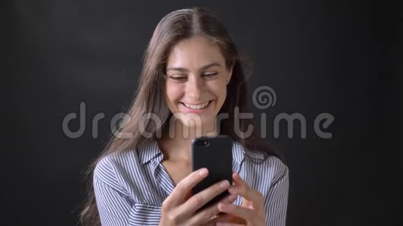 年轻的美女通过手机视频聊天说话微笑被隔离在黑色背景上视频的预览图