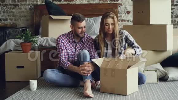 这对年轻夫妇很兴奋他们正在整理东西打开盒子拿个人物品搬到新公寓后交谈视频的预览图