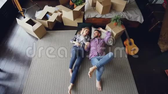 一对可爱的年轻夫妇躺在卧室的新公寓地板上聊天亲吻和拥抱视频的预览图