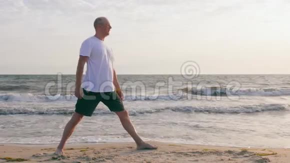 运动员在海边的伸展三角帆索练习瑜伽视频的预览图