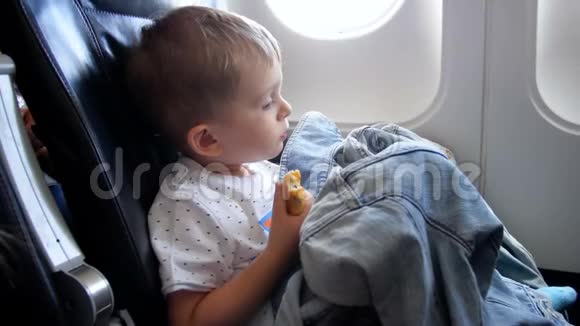 在飞机上长时间飞行时疲惫困倦的小男孩在吃包子视频的预览图
