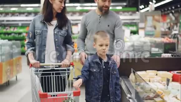 母亲父亲和儿子幸福的一家人正在超市的乳制品部门挑选奶酪他们正在从视频的预览图