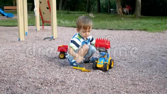 小男孩在公园玩玩具塑料装载机和拖车的4K镜头视频的预览图